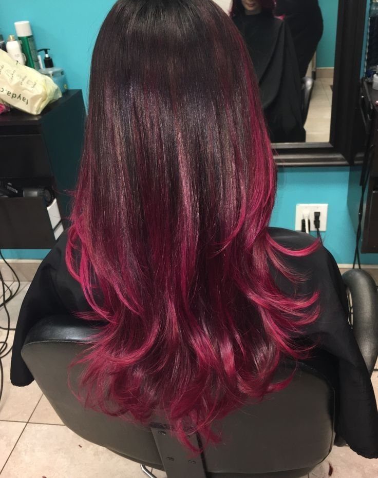 Long dark burgundy hair with vivid magenta highlights and curled pink ends in a salon