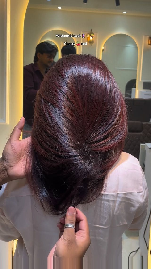 Dark burgundy hair gathered into a low twist in a salon