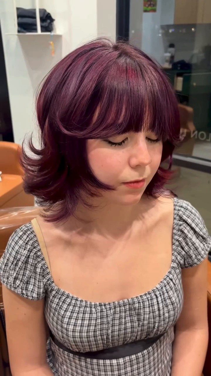 Person with a cherry-red bob, full bangs, and curled-under ends