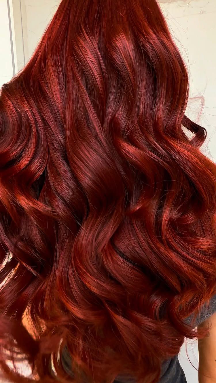 Long copper-red and cherry-red hair falls in glossy, voluminous curls