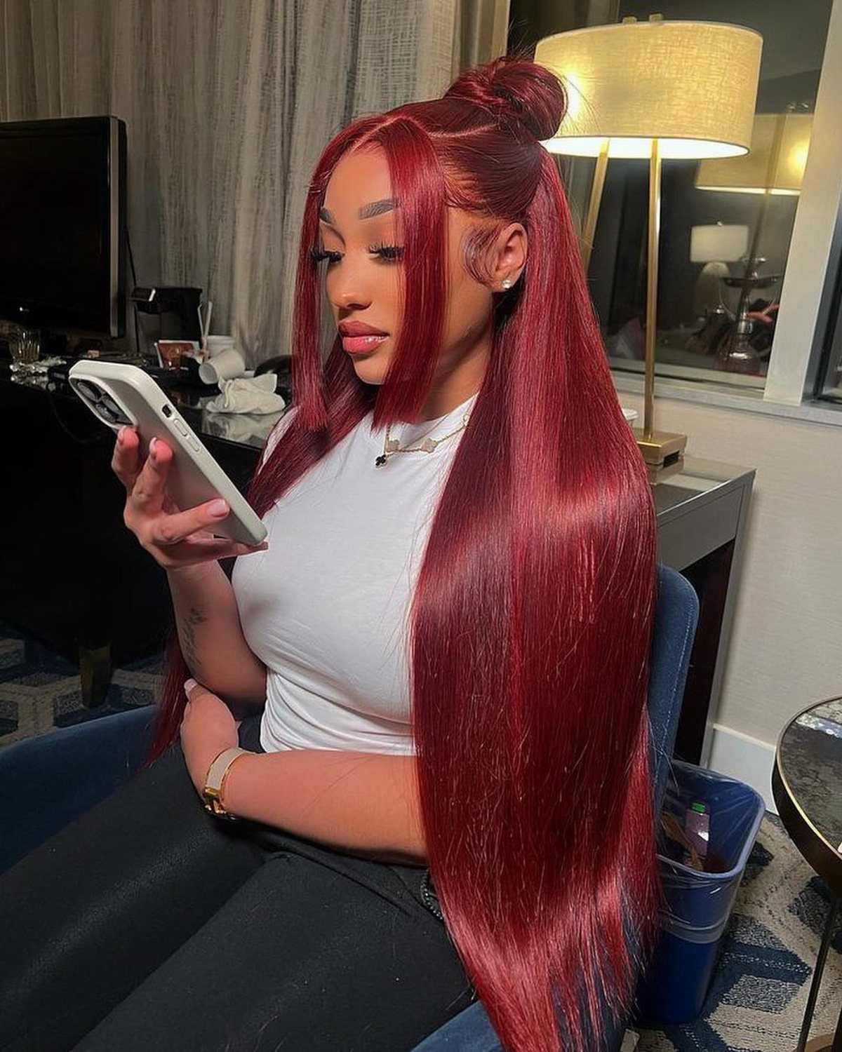 Woman with cherry-red hair in a high bun and long straight lengths