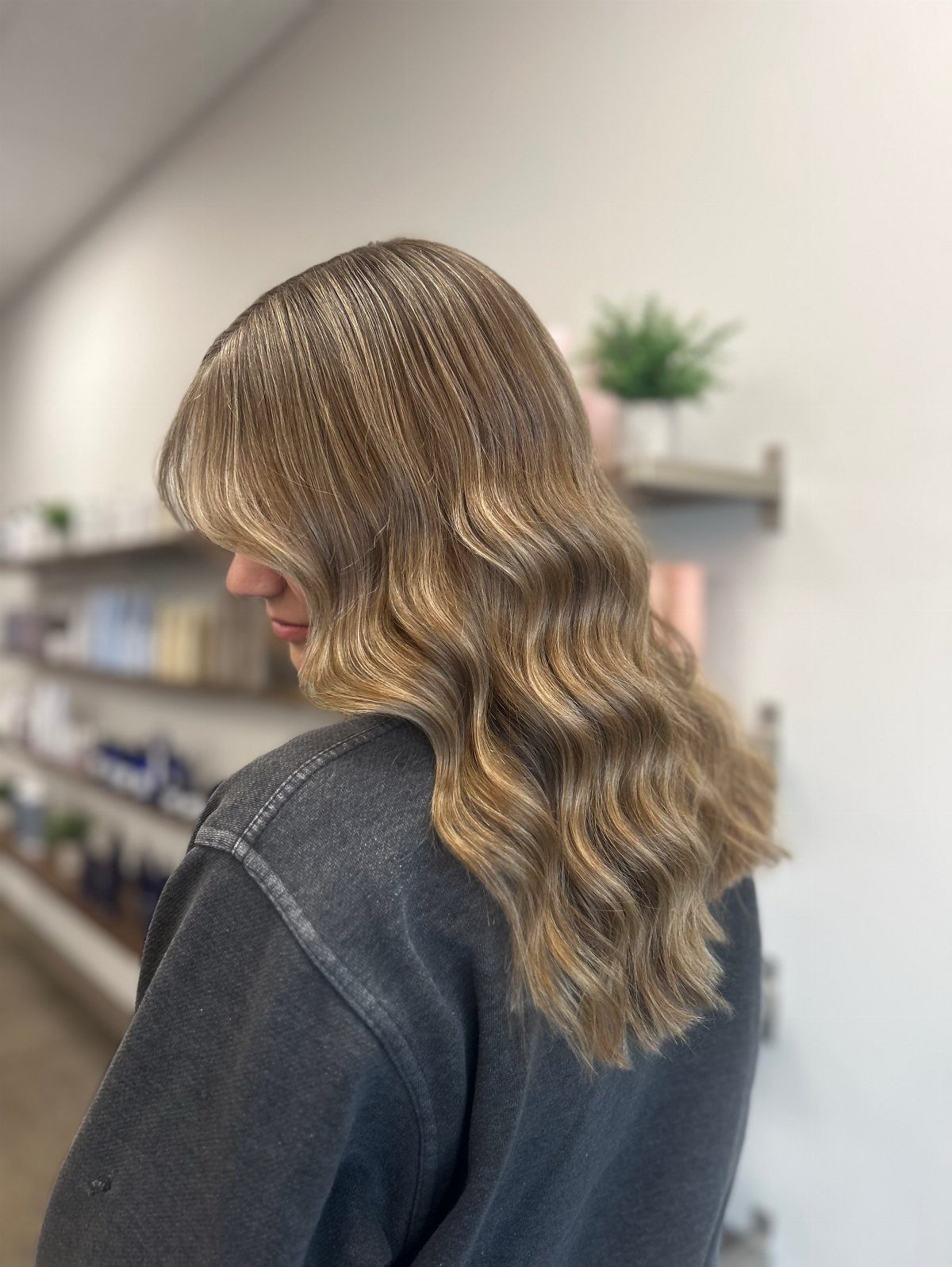 Wavy light-brown balayage hair with soft blonde highlights in a salon