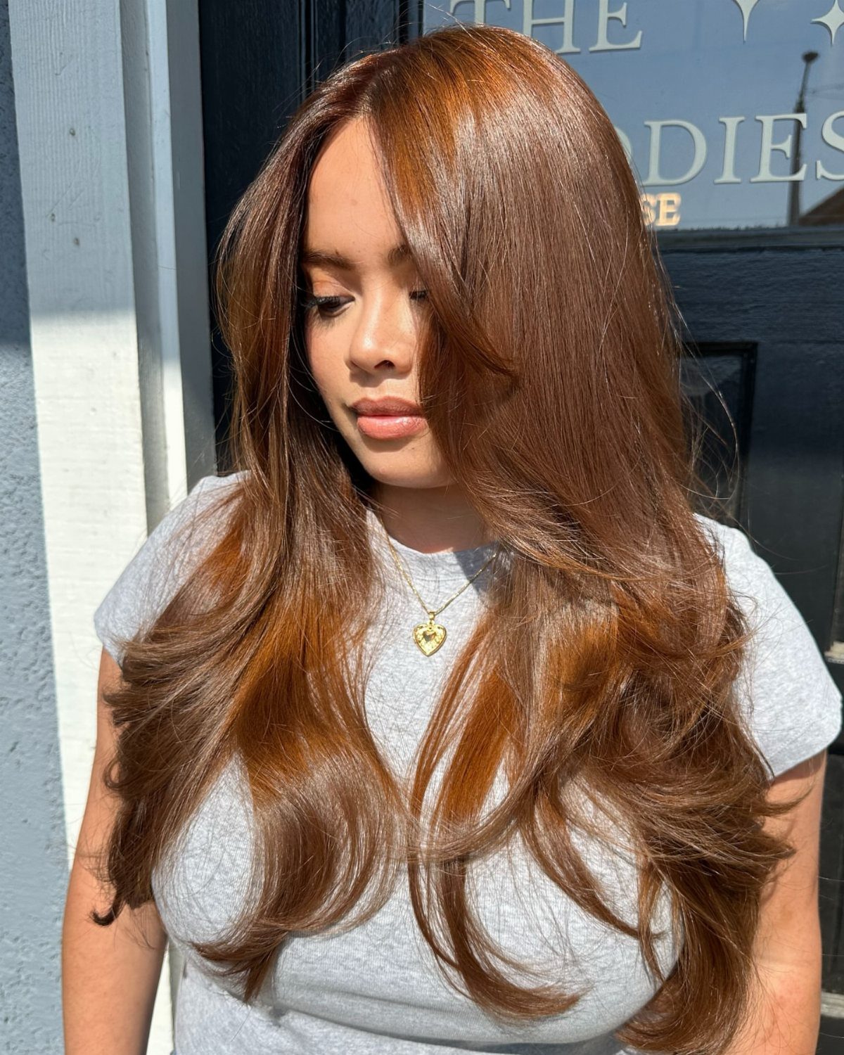 Woman with long, glossy reddish chestnut-brown hair and golden highlights