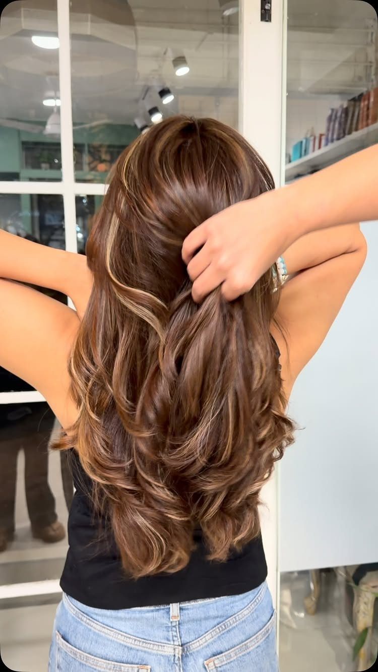 Dark chestnut hair with golden-brown highlights styled in long curls