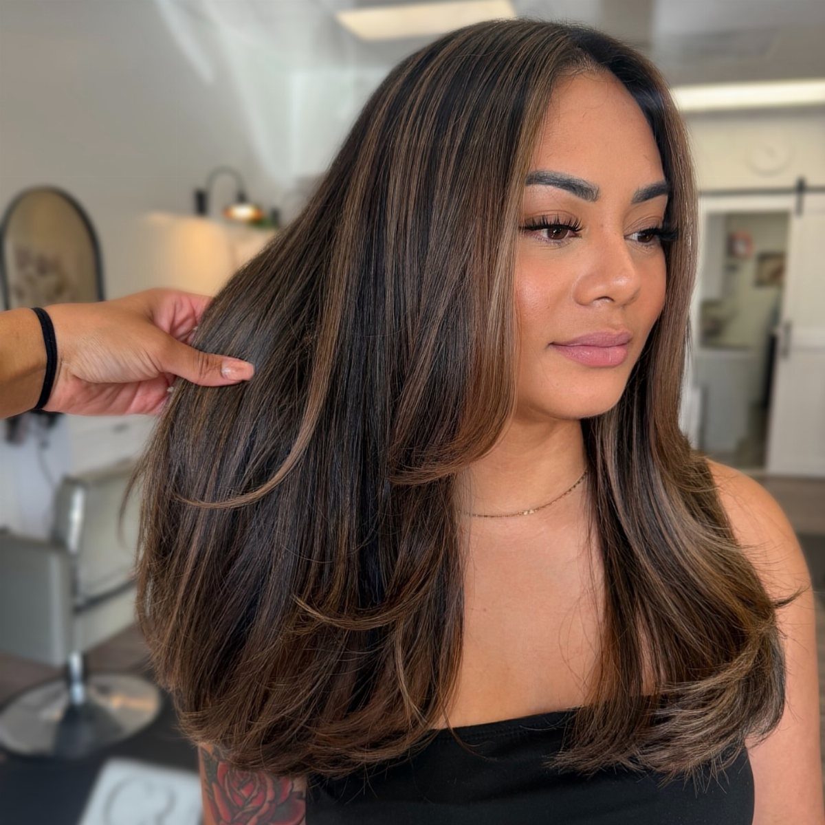 Woman showing glossy dark chocolate hair with warm chestnut balayage highlights