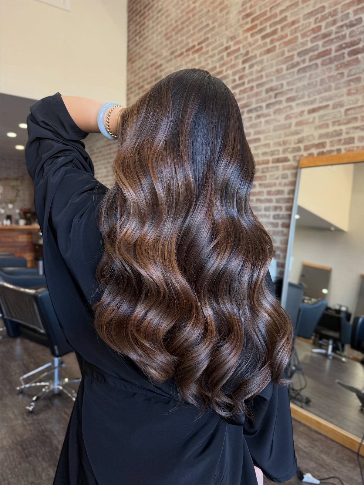 Long wavy dark brown hair with lighter milk chocolate highlights in a salon