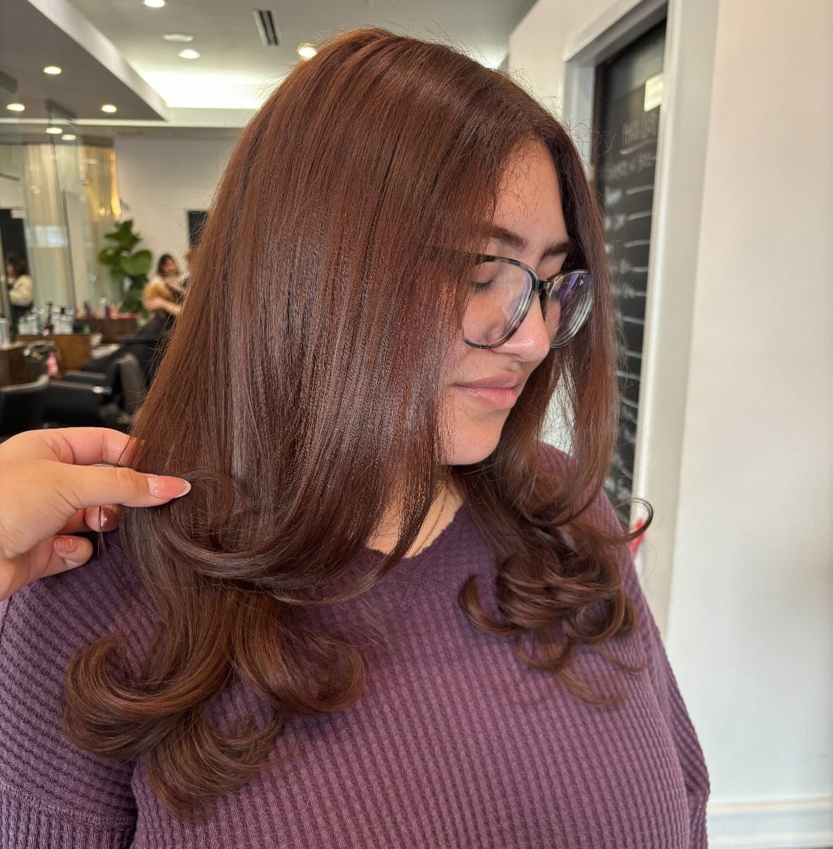 Reddish chestnut hair styled in glossy, loose curls in a salon