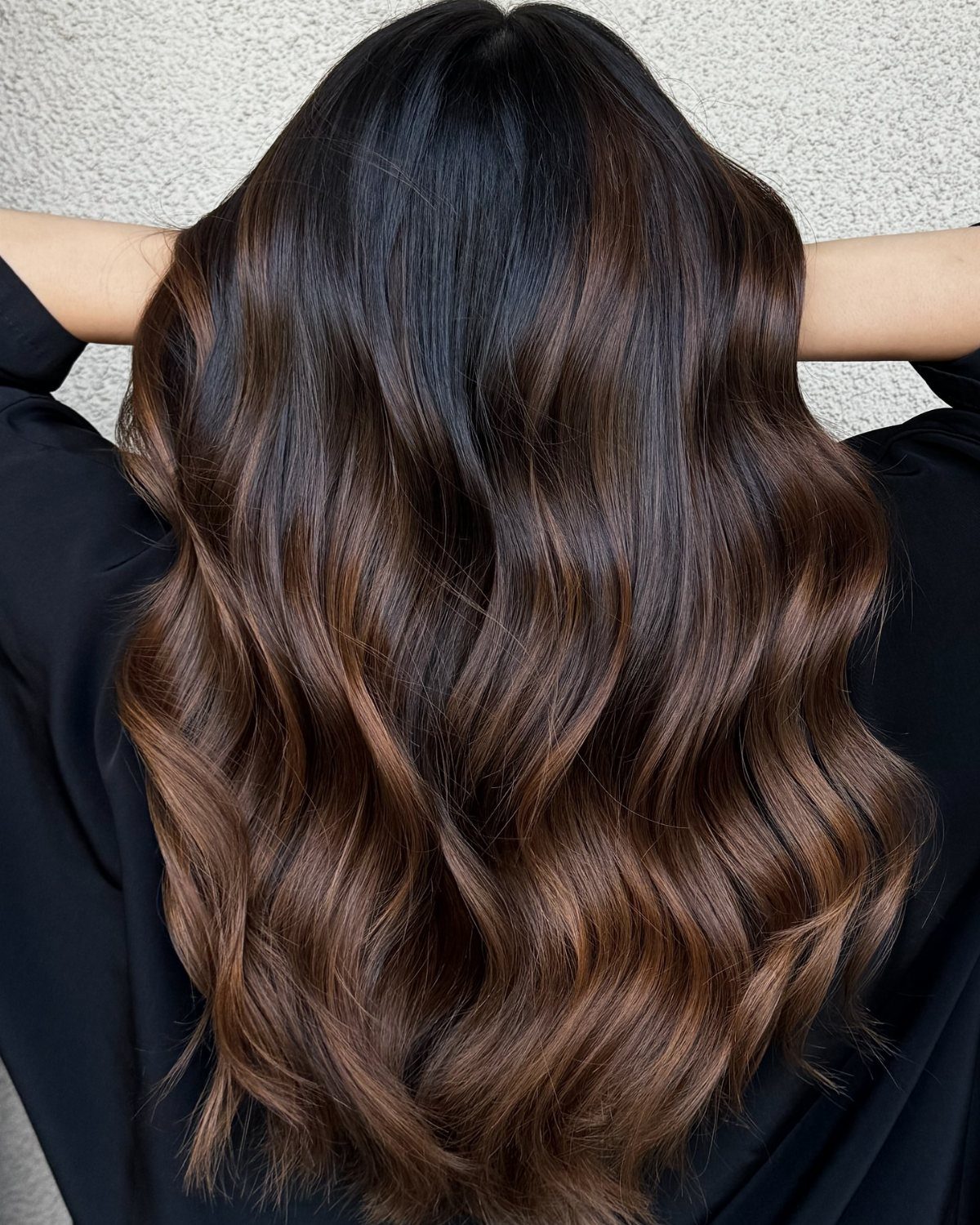 Wavy dark brown hair with warm chestnut balayage highlights