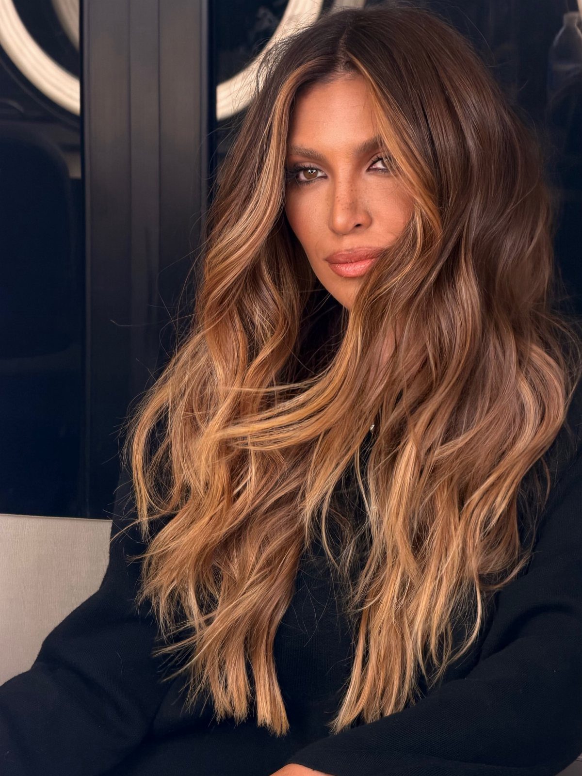 Woman with long brown hair and vivid caramel balayage highlights
