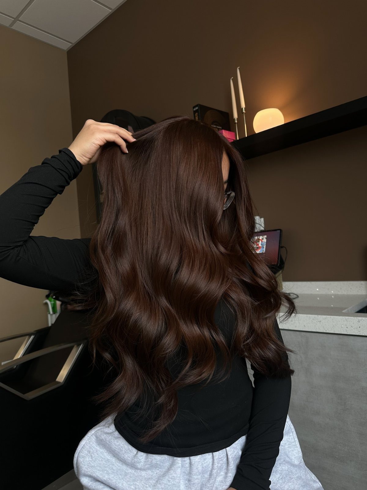 Long warm dark brown waves shown from behind in a salon chair