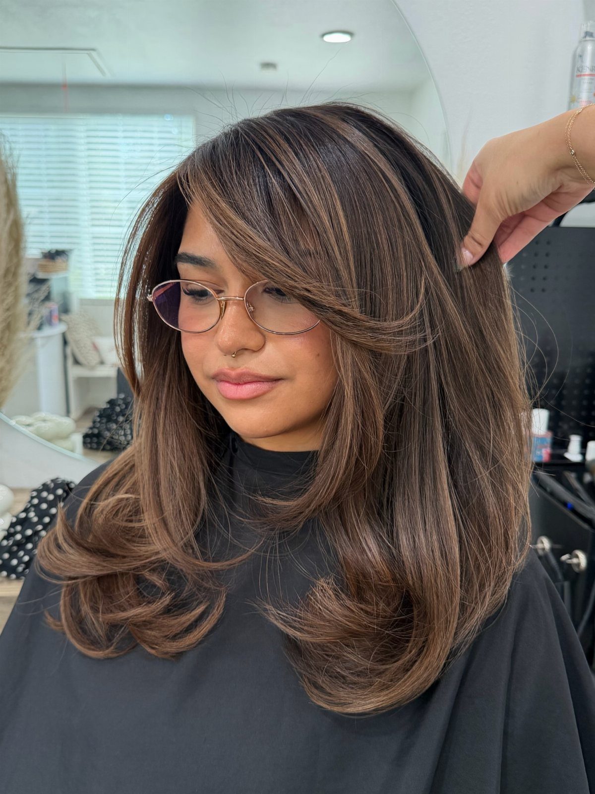 Chestnut-brown layered hair with subtle lighter face-framing pieces in a salon