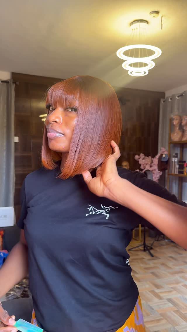 Woman showing a sleek reddish-brown elongated bob with blunt bangs