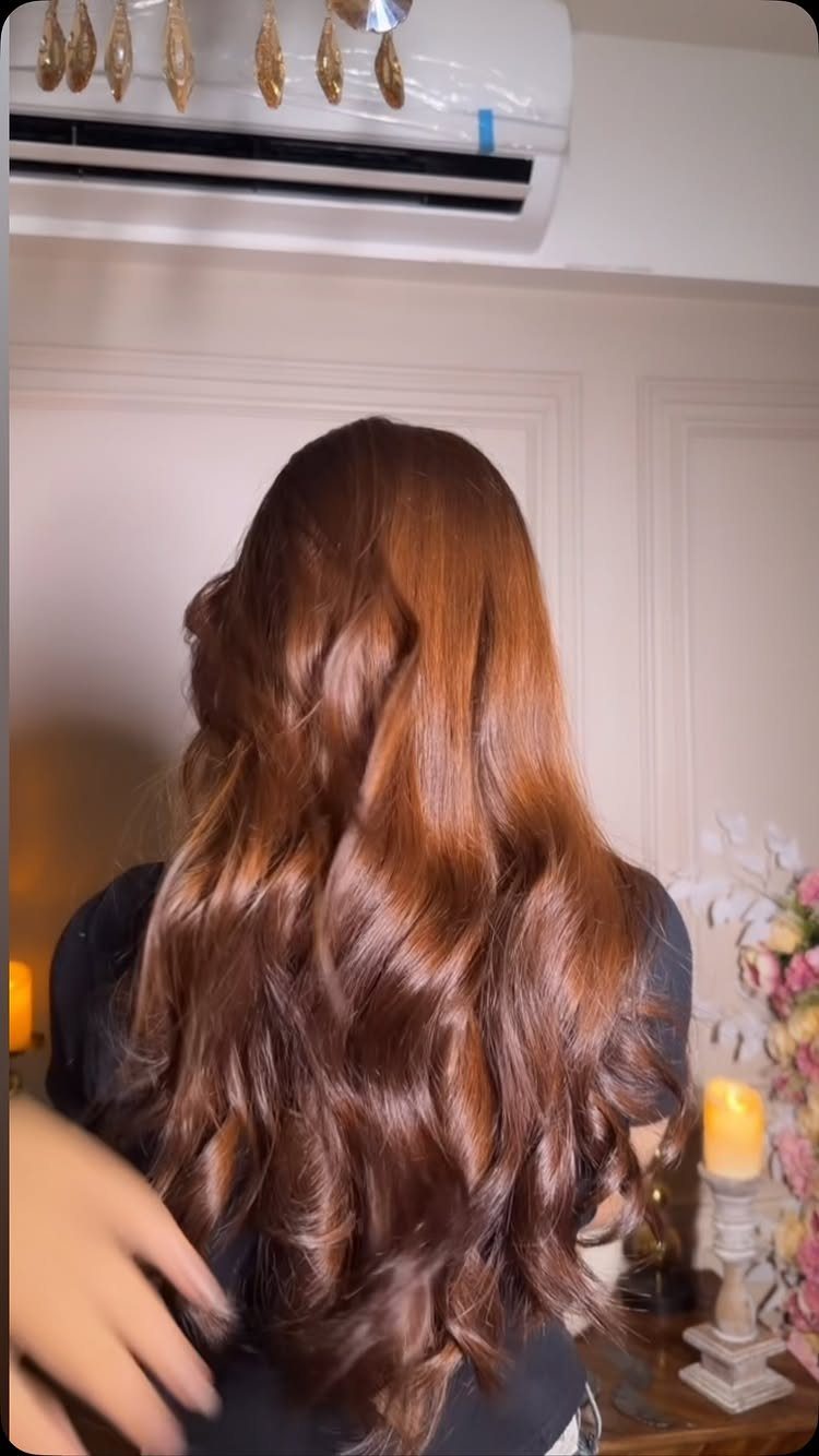 Long chestnut curls show subtle golden tones in a salon