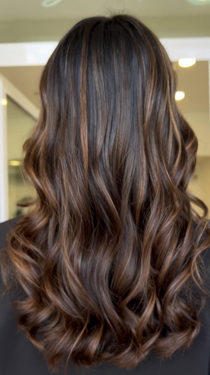 Long wavy brunette hair with cool cinnamon balayage highlights and curled ends