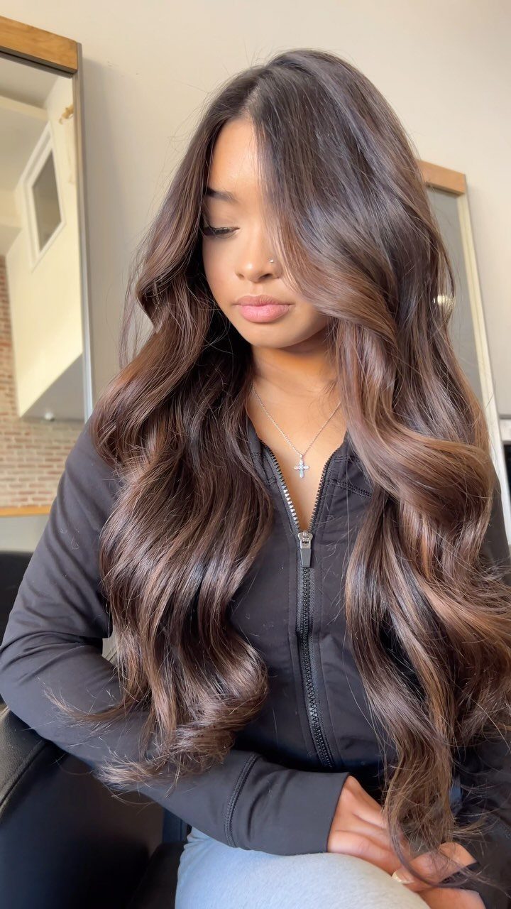 Woman with long, wavy deep cocoa-brown hair and subtle dimensional highlights