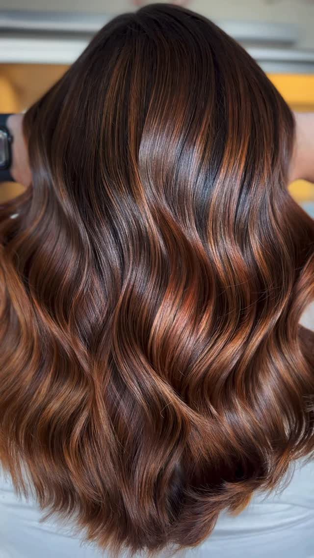 Wavy chocolate-brown hair with subtle blended copper highlights