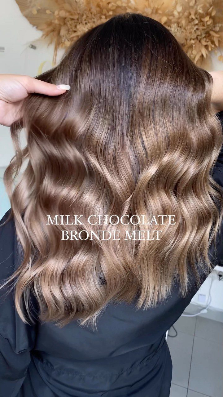 Wavy brunette hair with creamy lighter highlights and a soft, dimensional blend