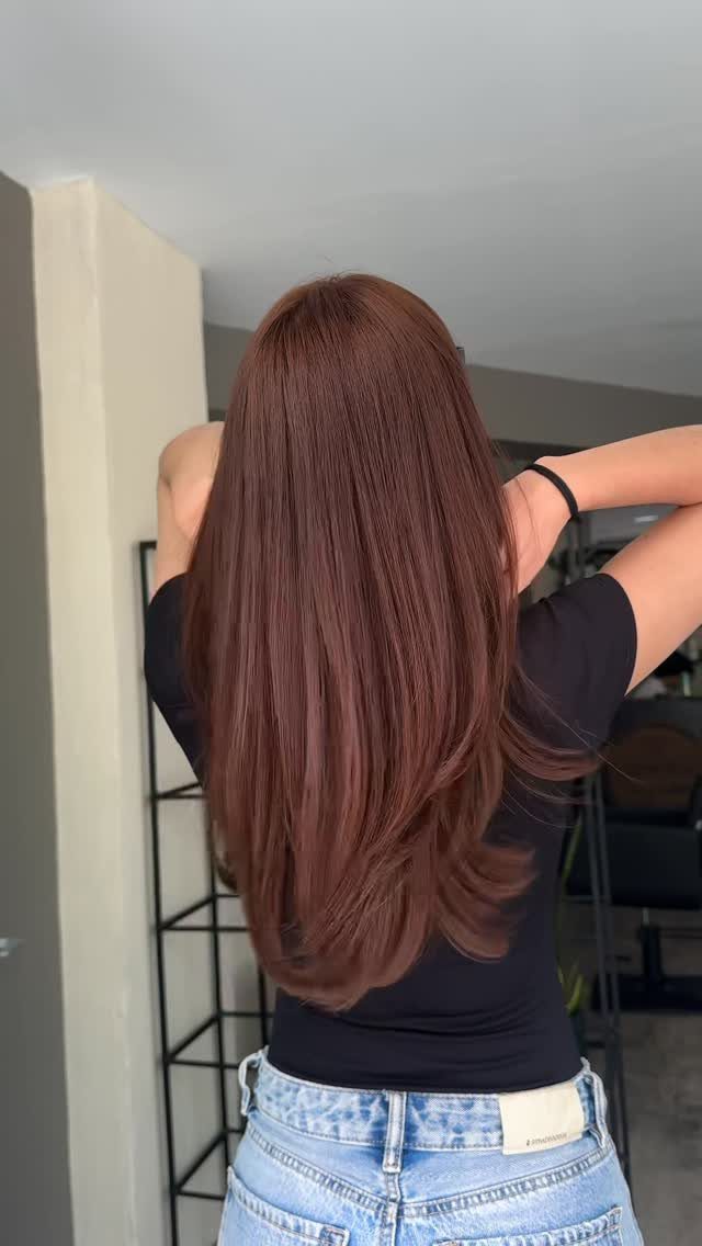 Long reddish-brown hair falls smoothly down the back over a black top