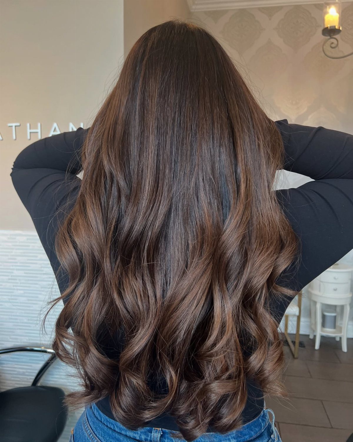 Long dark chocolate-brown hair falls in glossy, loose waves down a person's back.