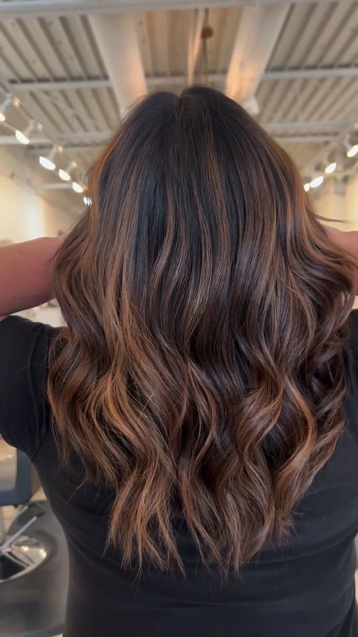Wavy chocolate brown hair with caramel ribbons in a salon