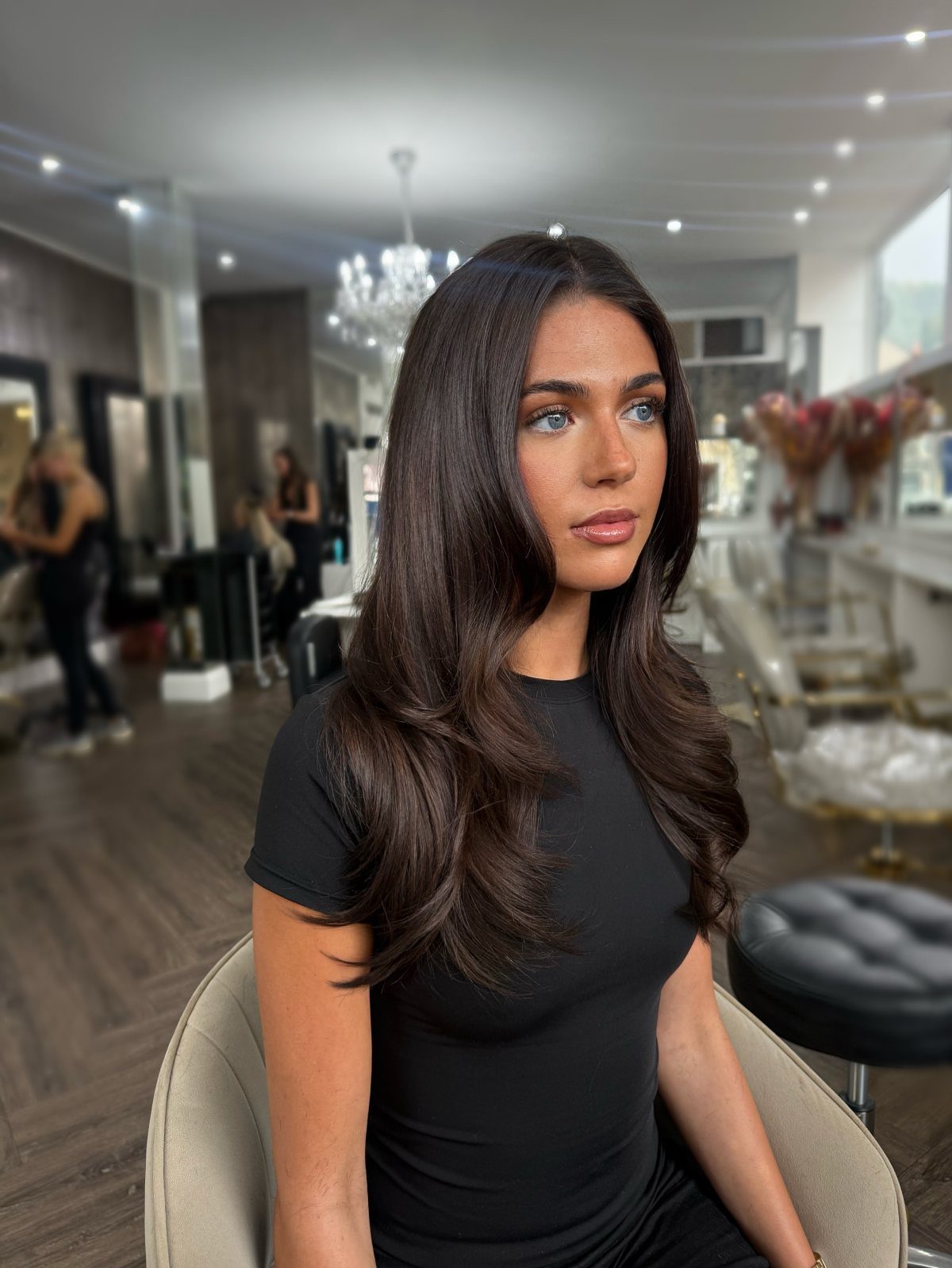 Woman with long glossy chocolate-brown hair seated in a salon