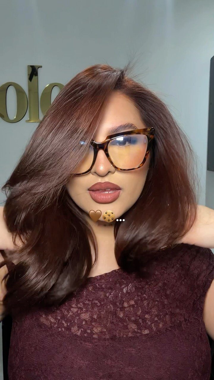 Woman showcasing long chocolate brown hair with warm cinnamon-copper tones and oversized sunglasses