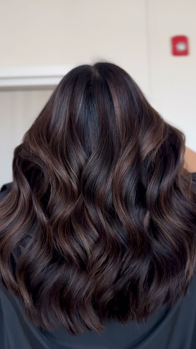 Dark espresso-brown wavy hair with subtle chocolate-brown balayage highlights