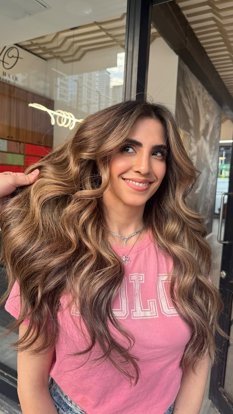 Woman showing long wavy brown hair with warm golden-bronze highlights