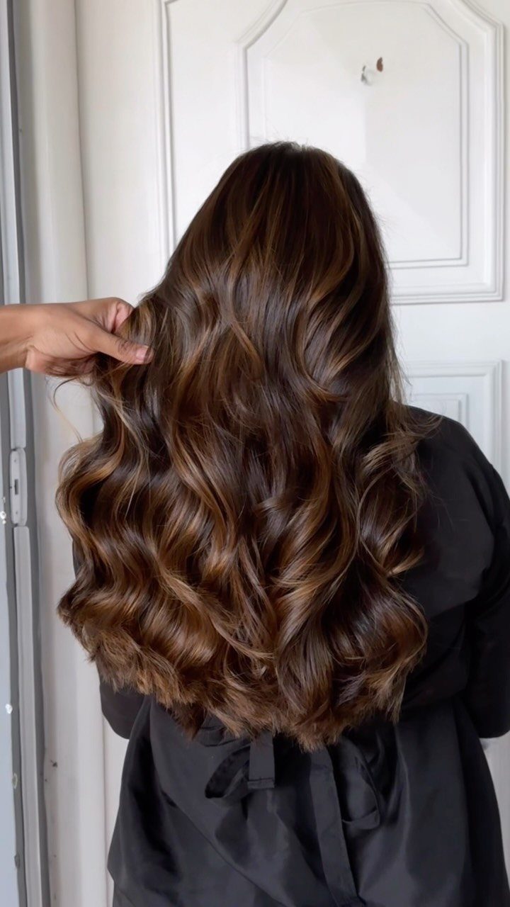 Long curled chocolate-brown hair with warm honey-toned highlights shown from behind