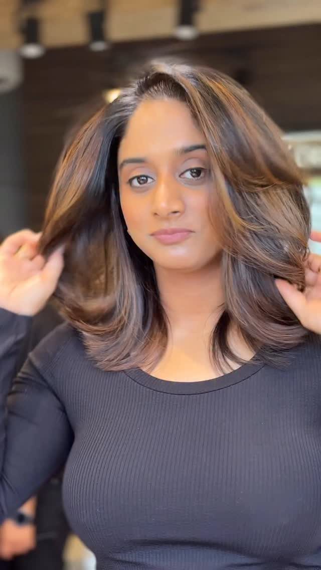 Woman displays long, voluminous light chocolate brown hair with warm highlights