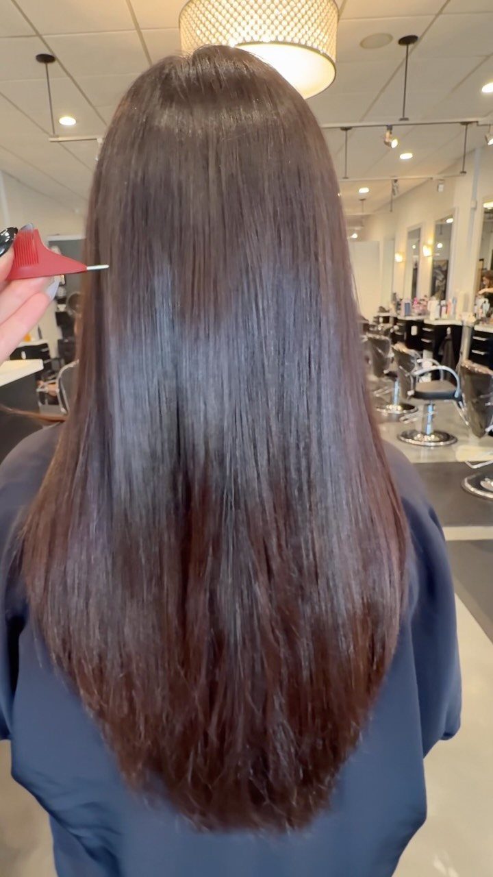 Long, cool-toned milk chocolate brown hair shown from behind in a salon