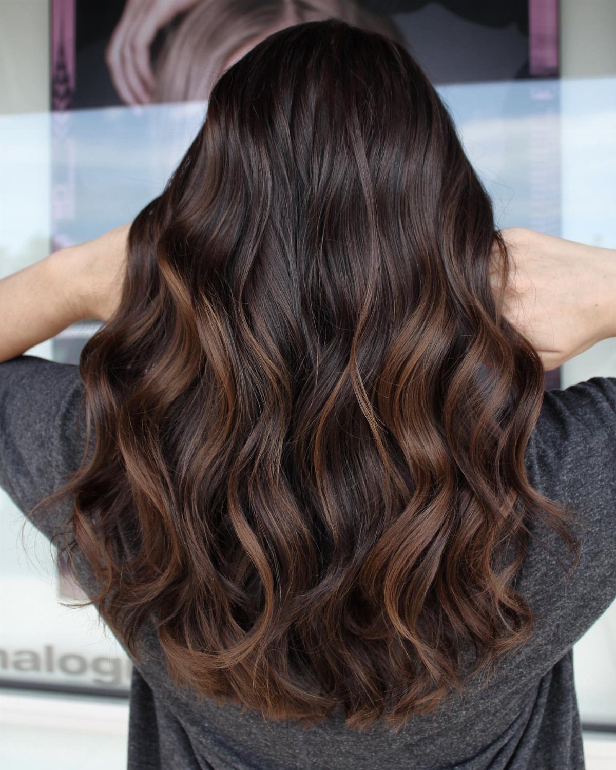 Wavy brunette hair blends dark roots with warm brown balayage strands