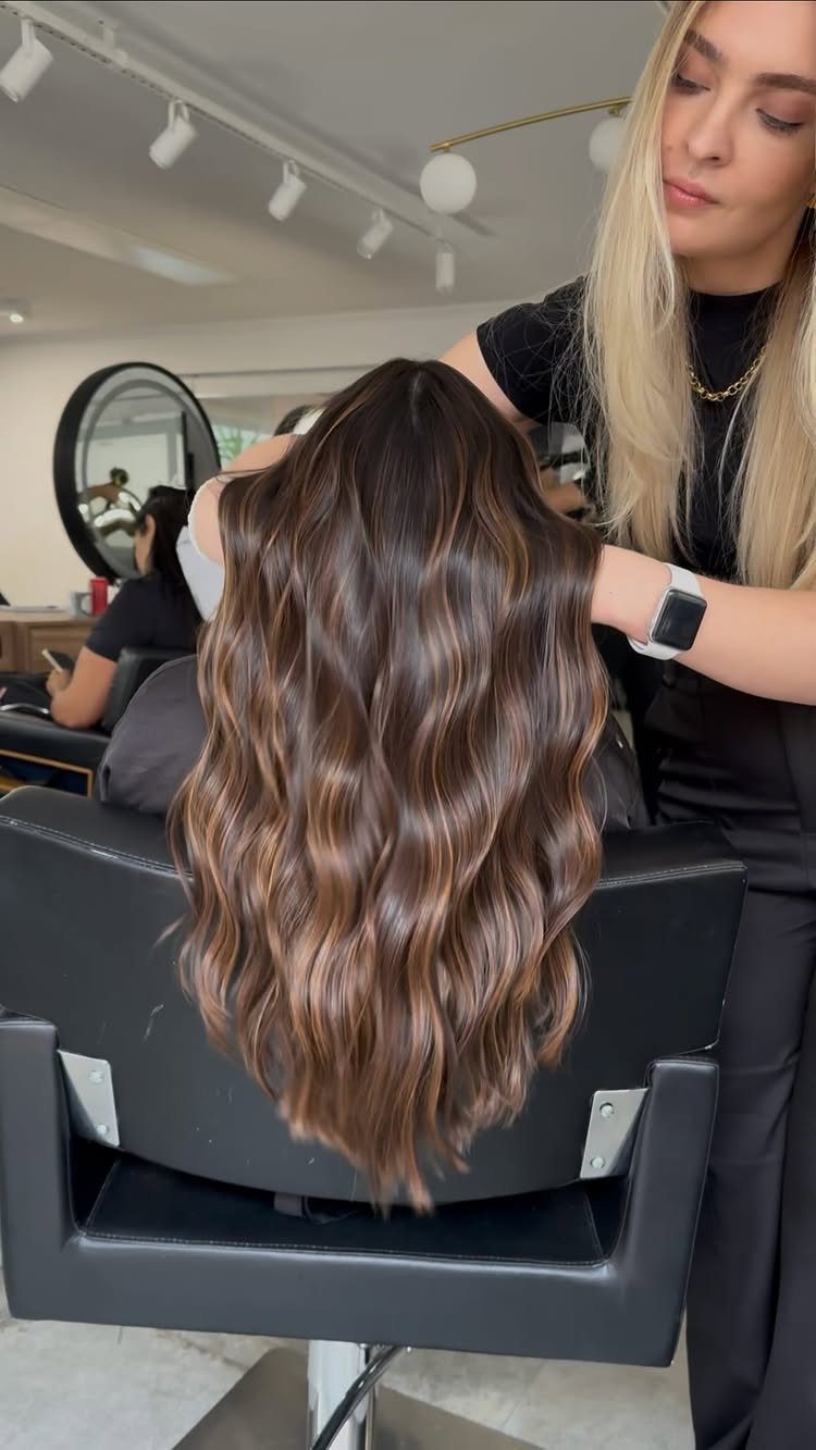 Wavy light chocolate-brown hair with warm toffee-colored highlights in a salon