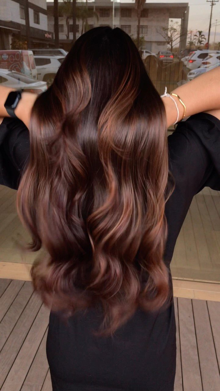 Long dark brown waves with shimmering copper-bronze highlights through the ends