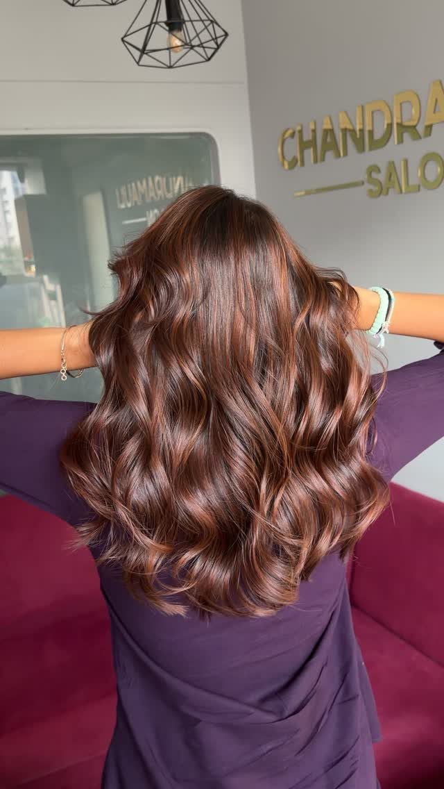 Wavy brown hair with dimensional copper balayage shown in a salon