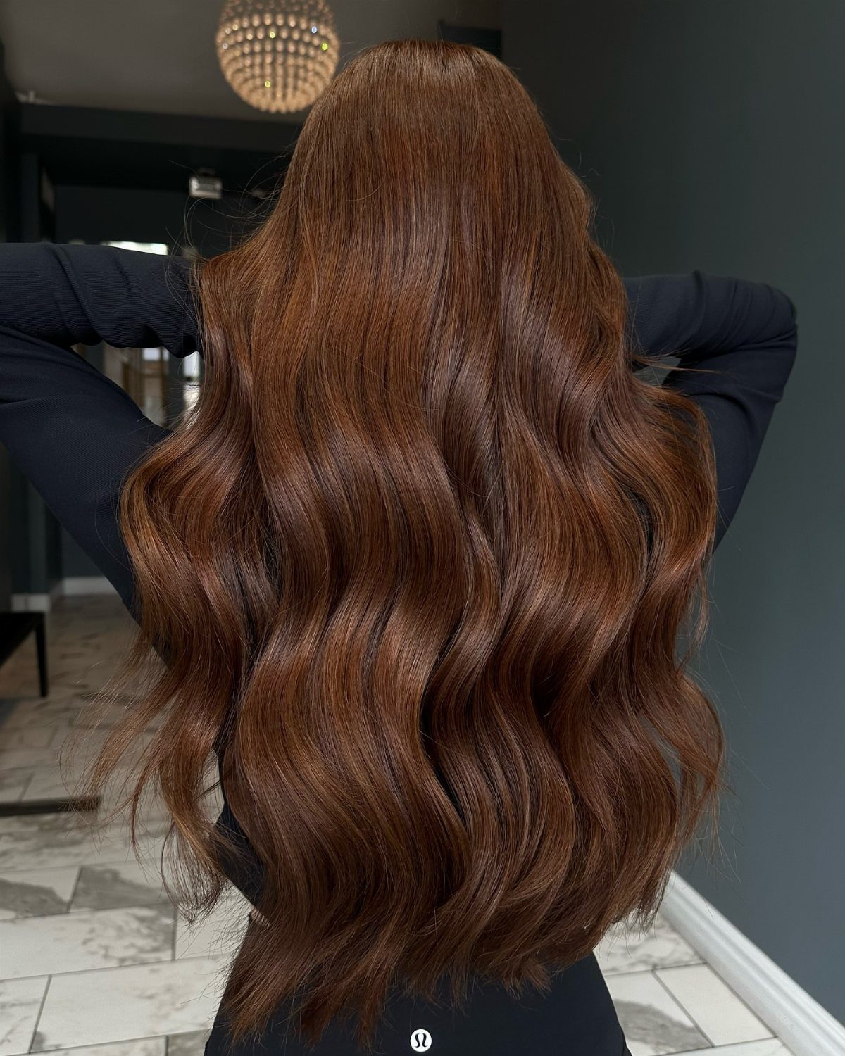 Glossy copper-brown hair cascades in long, softly waved strands