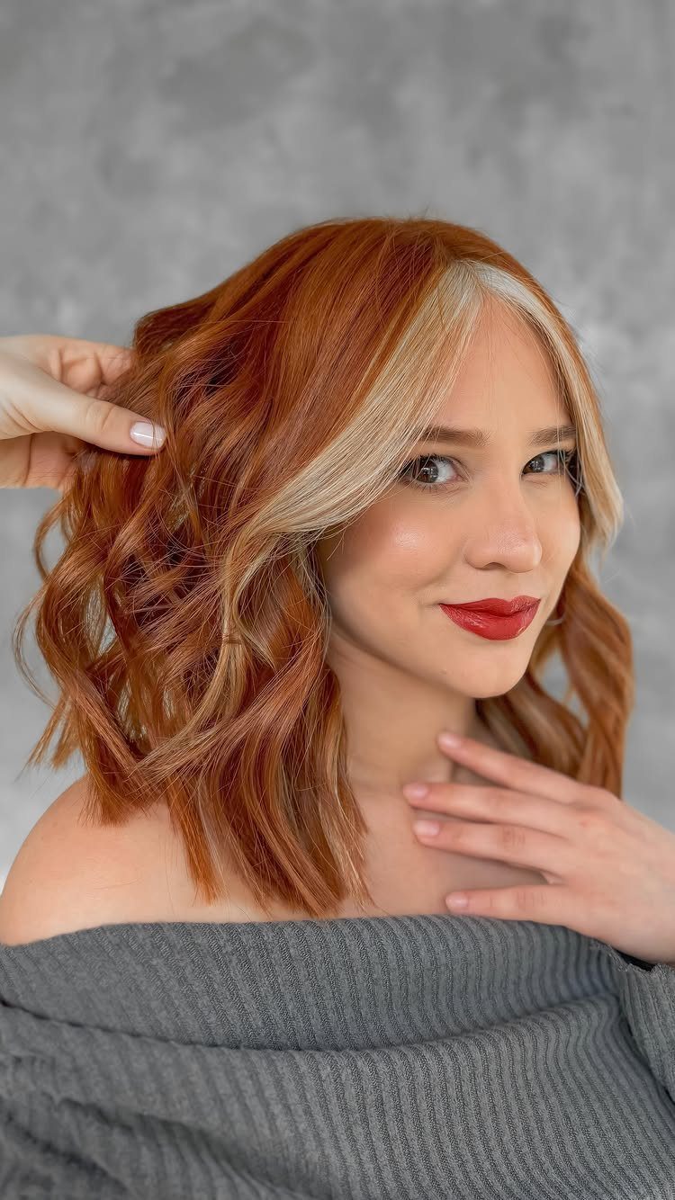Woman showing wavy copper-brown hair with lighter copper face-framing strands