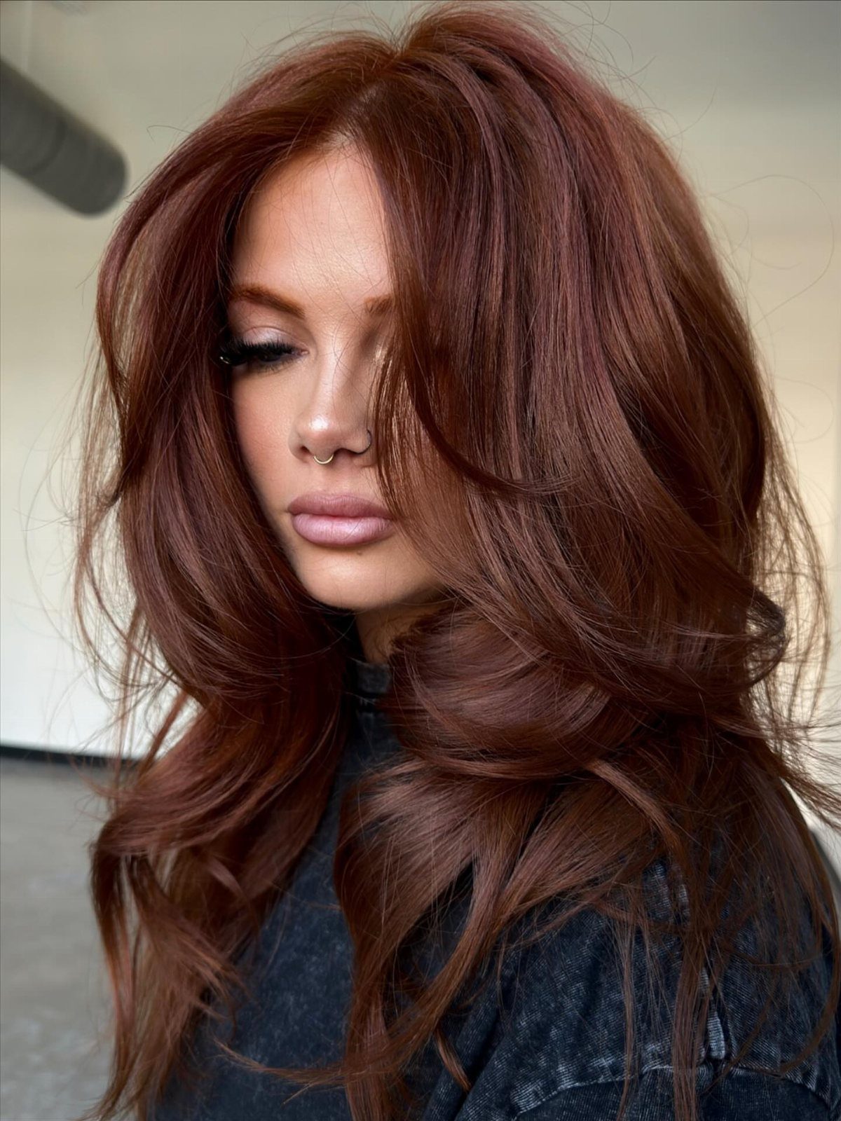 Woman with long, wavy dark copper-brown hair styled with warm reddish-golden tones
