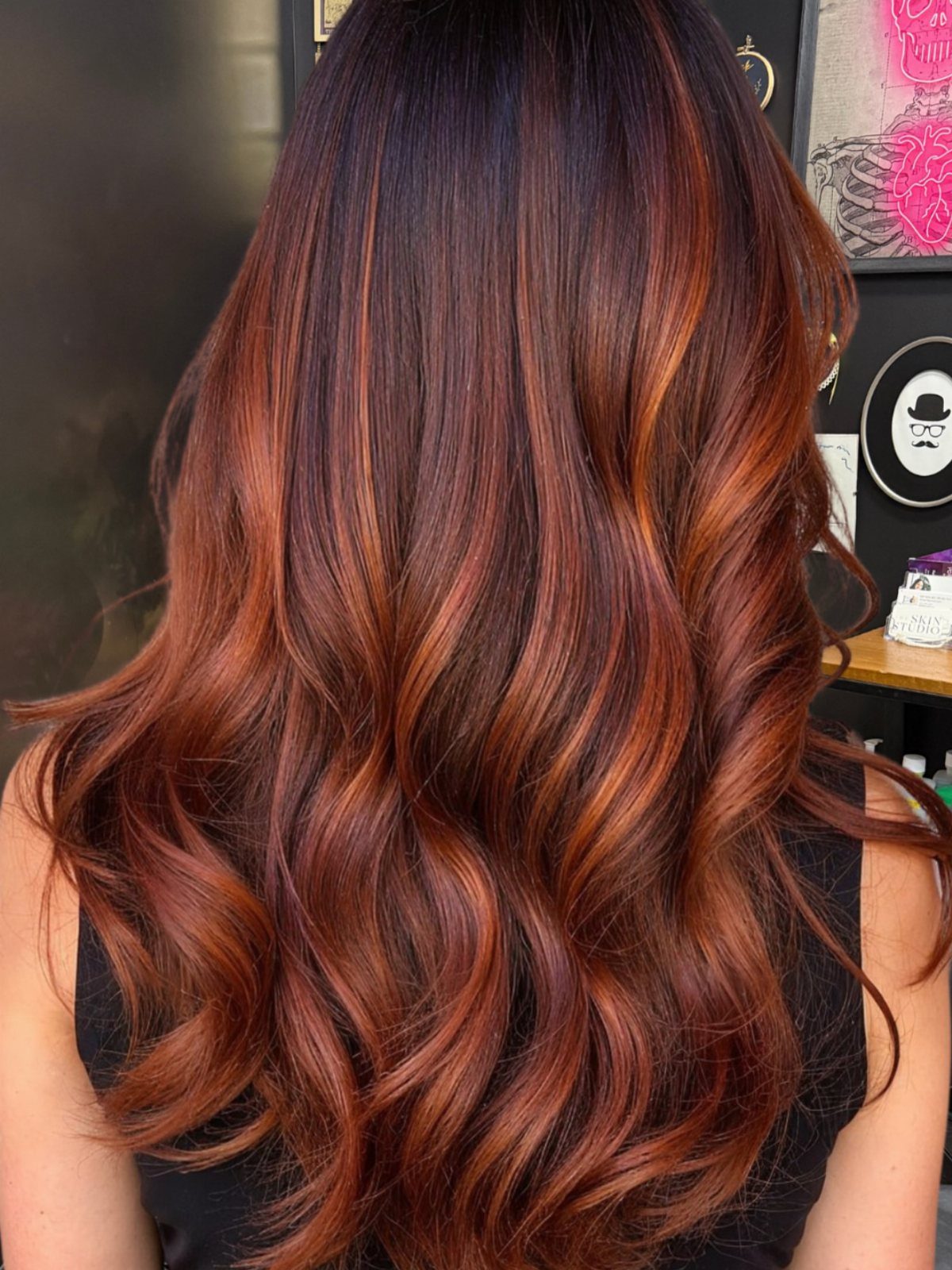 Long dark brown hair with vivid copper-red highlights in soft waves