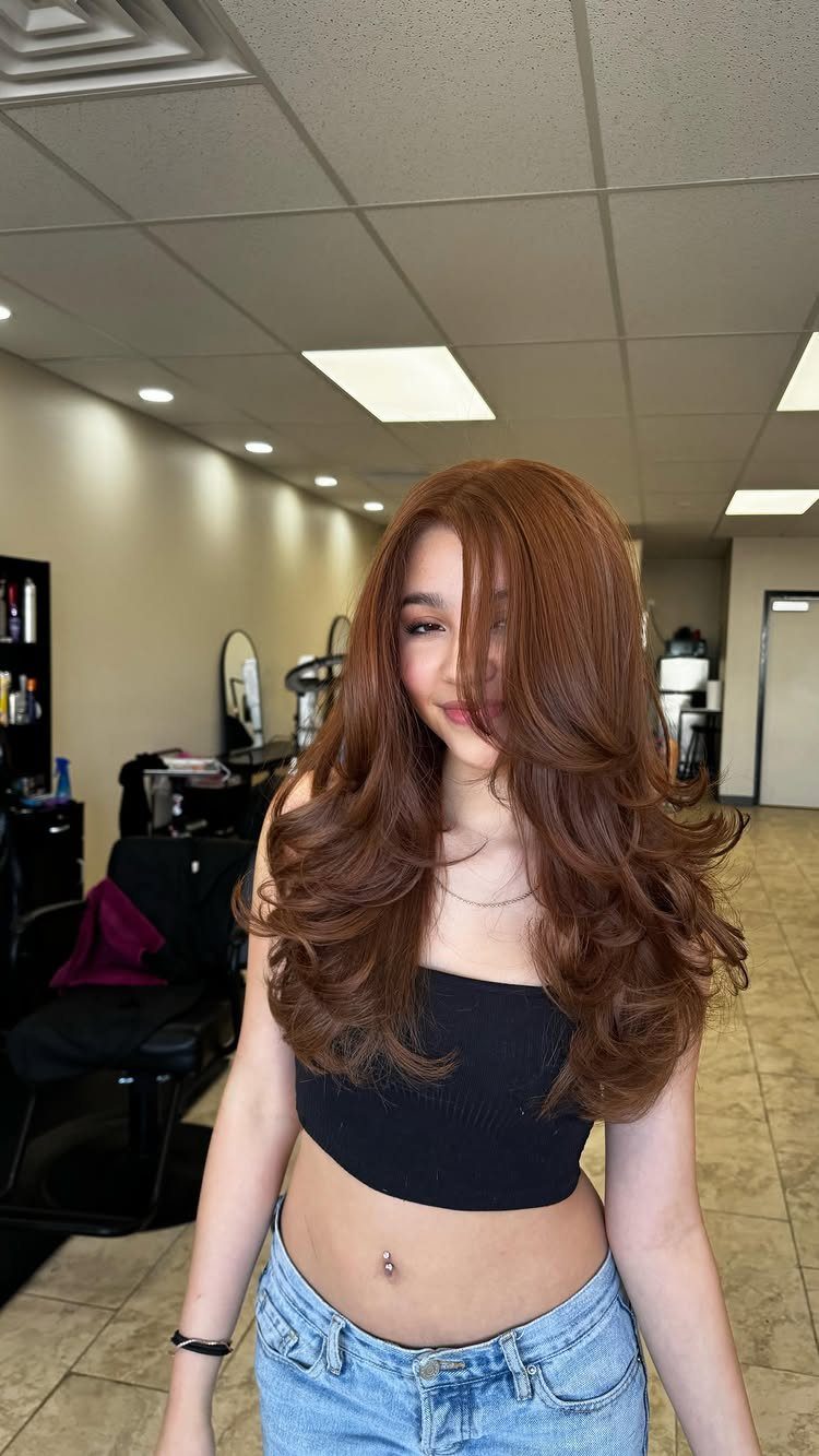 Woman with long, voluminous maple copper-brown hair standing in a salon