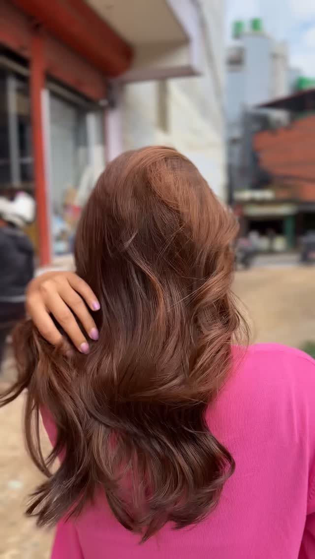 Long, wavy copper-brown hair shown from behind on a city sidewalk