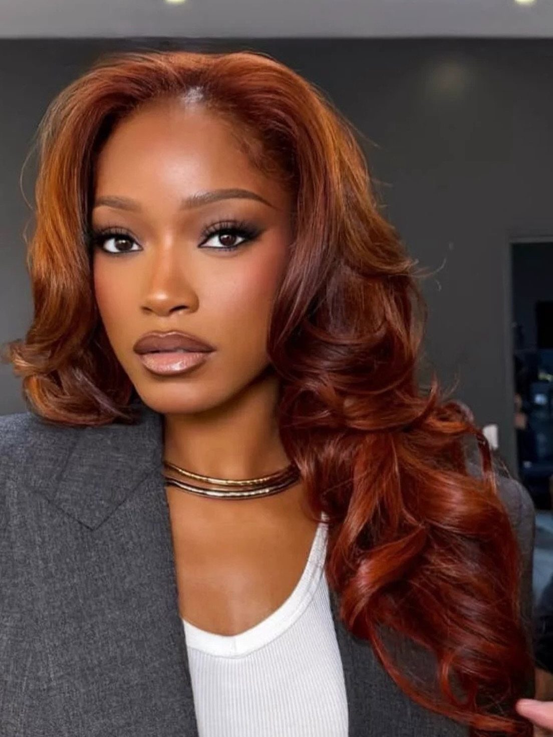 Woman with long, glossy copper-red waves and layered curls