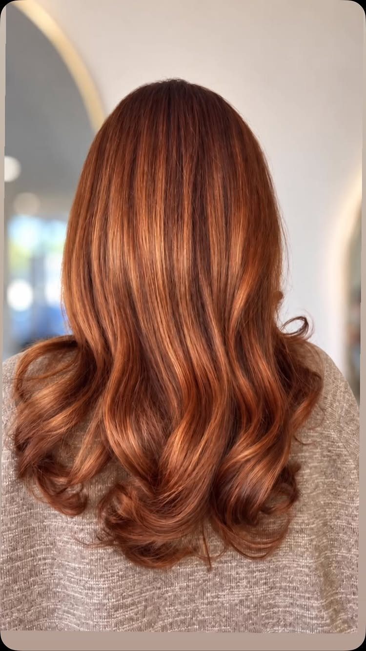 Long copper hair with darker roots and lighter balayage strands in loose curls
