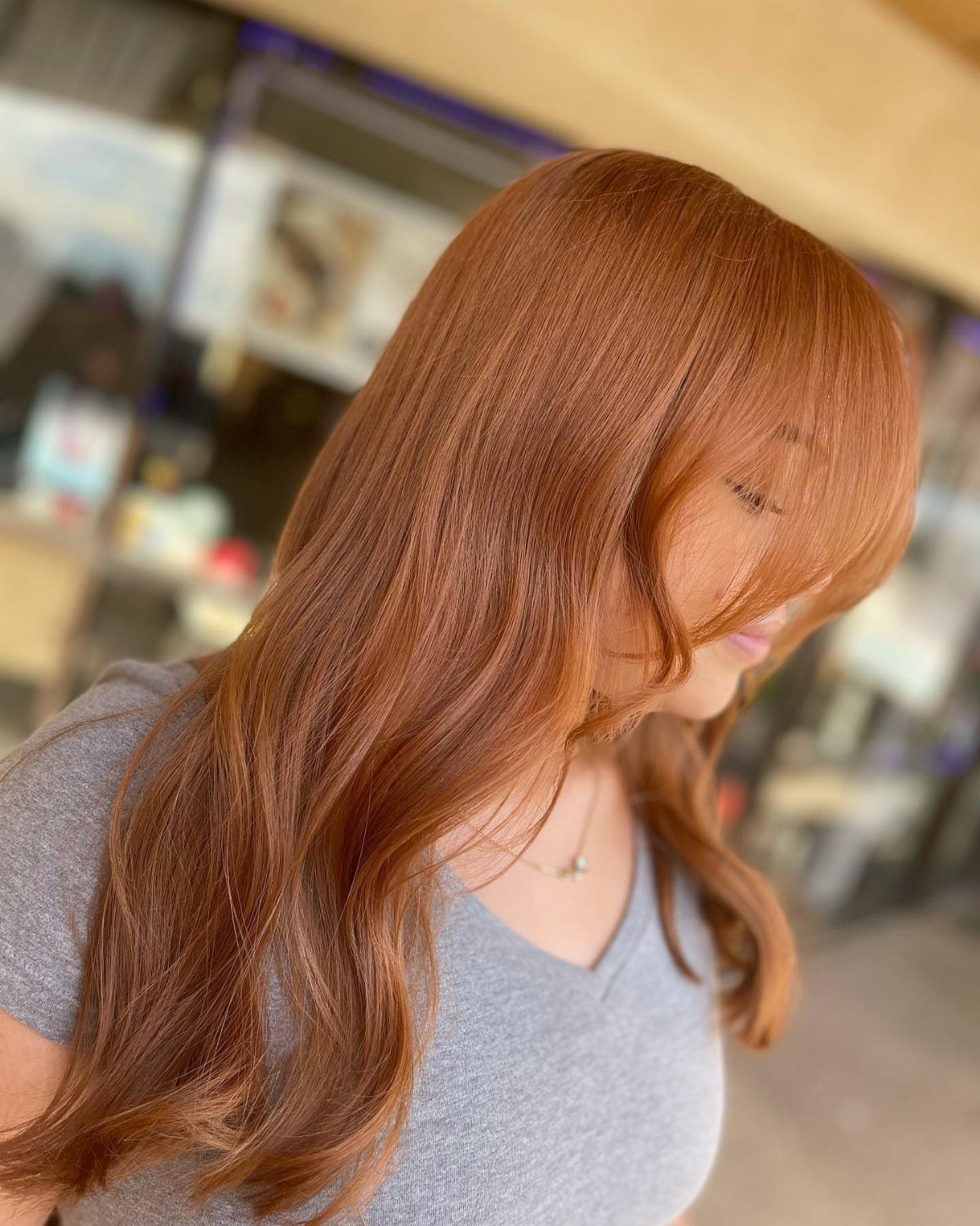 Long copper hair with sweeping curtain bangs styled in soft layers