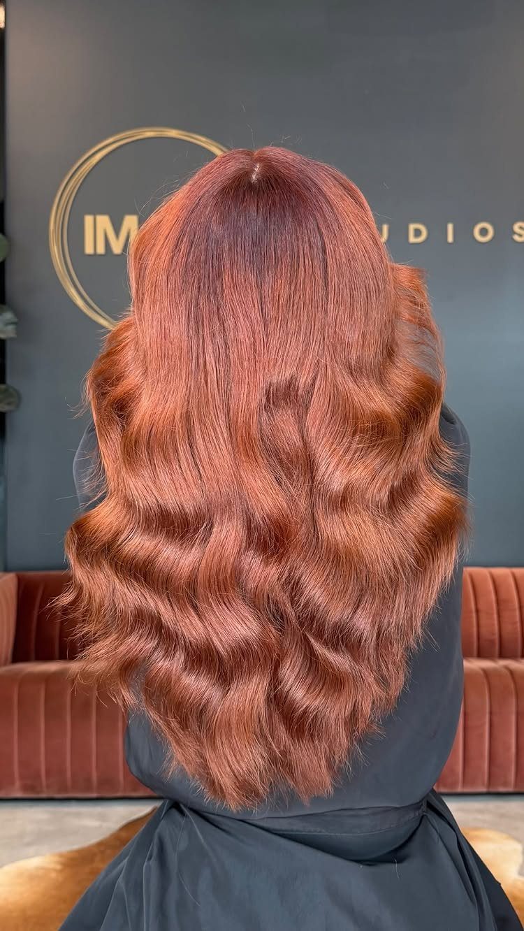 Long copper-red hair styled in glossy, loose waves at a salon