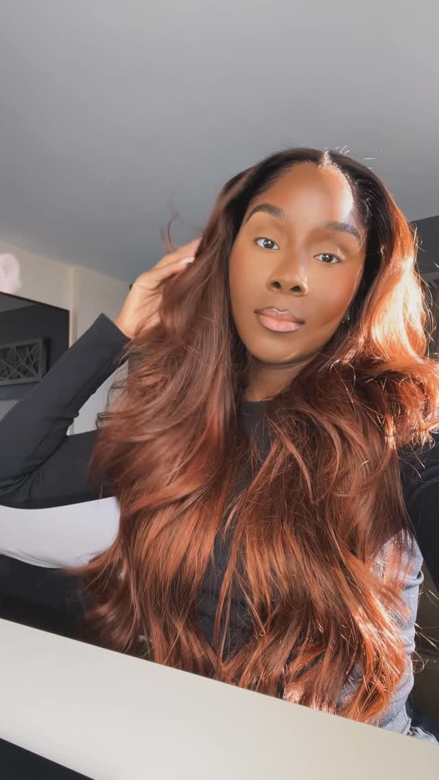 Woman displaying long, wavy dark brown hair with bright copper highlights