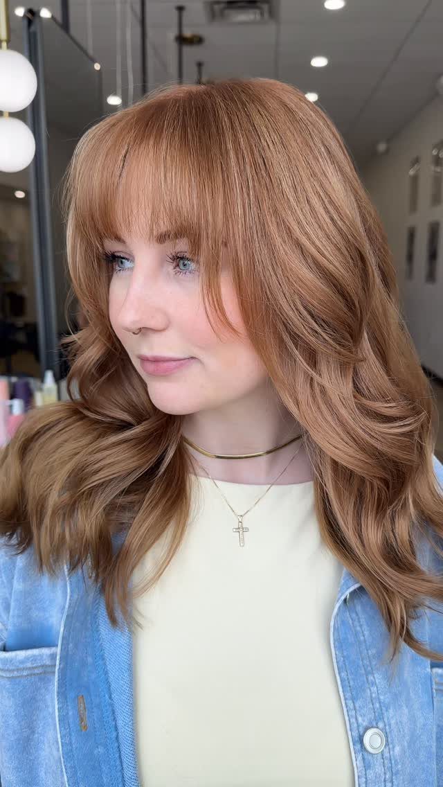 Woman with long ginger copper layers and curtain bangs in a salon