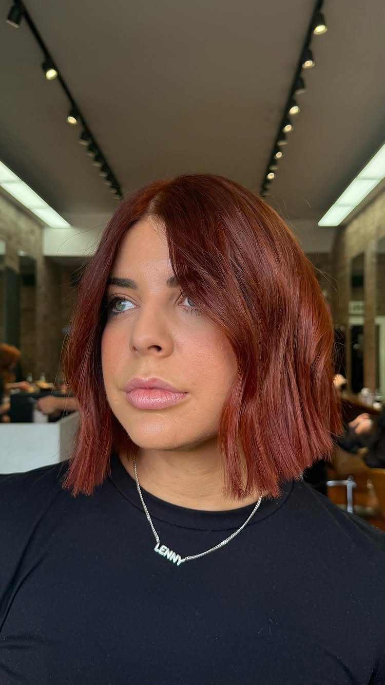Woman with a bright copper bob and curtain bangs in a salon