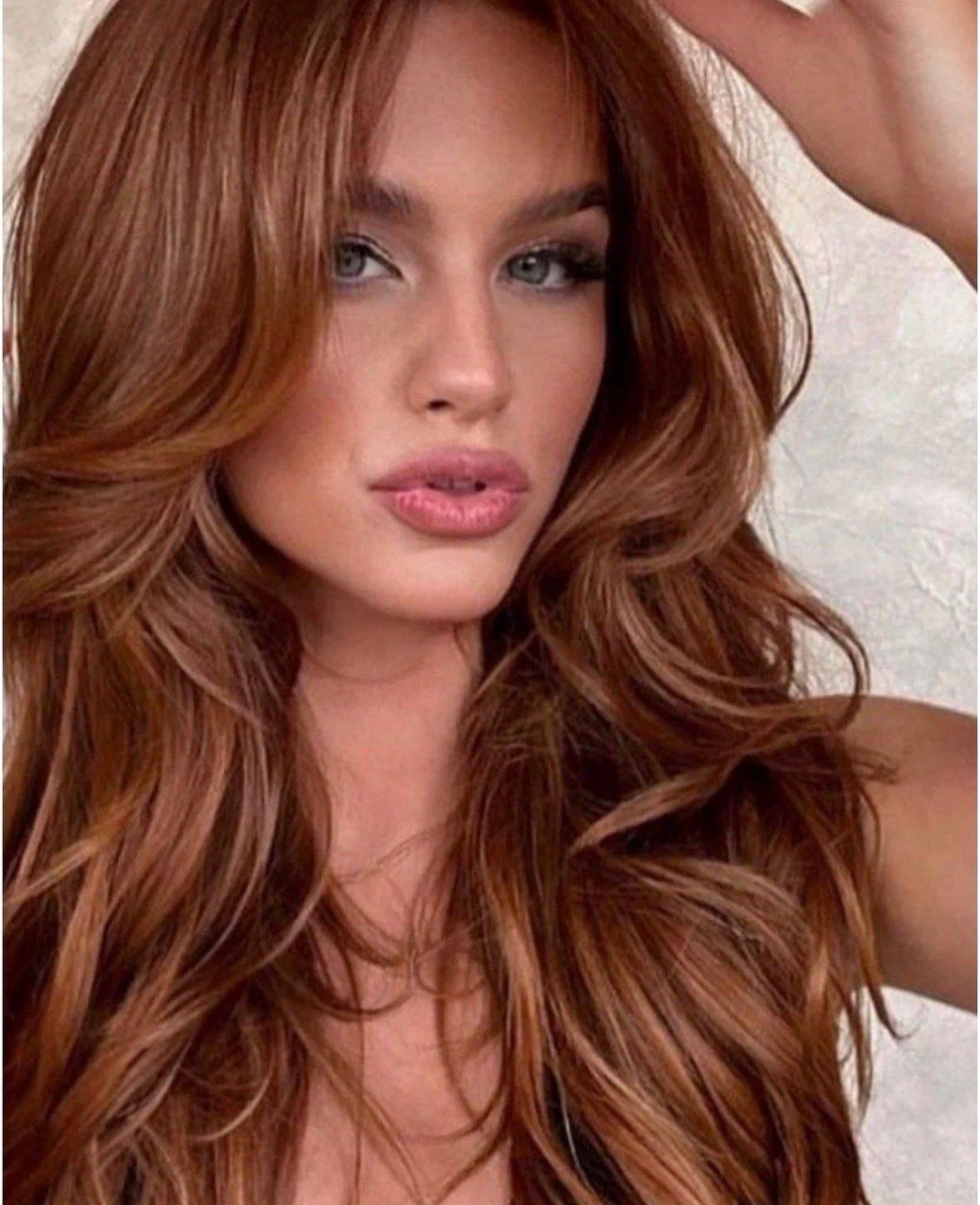 Woman with long layered warm copper-brown hair and brighter reddish accents