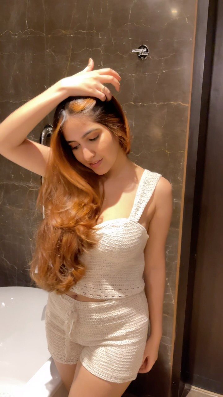 Woman displaying long, wavy copper hair with lighter golden strands